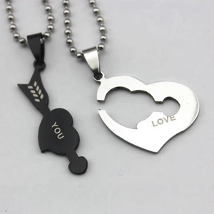 Close-up of interlocking heart and arrow pendants in black and silver stainless steel