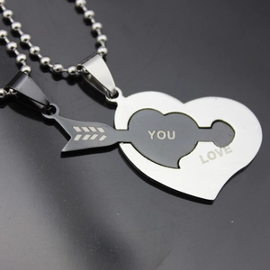 Detailed close-up of stainless steel couple necklaces with LOVE YOU heart and arrow pendants