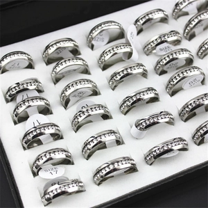Array of silver stainless steel rings with clear crystals shown in a display box with size tags