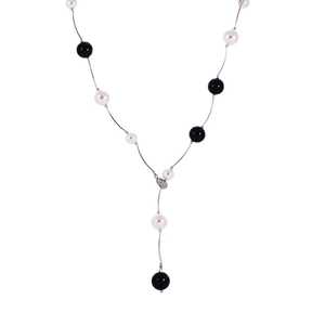 Détail d'un long collier en Y avec perles blanches, perles noires et pendentif cœur