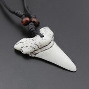 Macro detail of shark tooth pendant with natural black spots and red wood beads