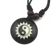 Macro shot of Yin Yang pendant with black cord and brown wooden beads detail