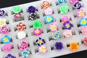 Detailed view of colorful clay flower rings with adjustable metal bands on a display tray