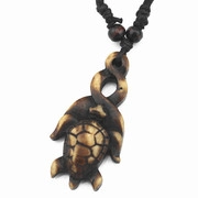 Detailed view of the handcrafted turtle pendant with brown texture and black braided cord