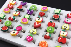 Close-up of adjustable kids clay rings featuring colorful fruit patterns in a display tray