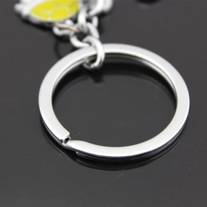 Macro detail of a bright silver split metal key ring with a yellow enamel charm