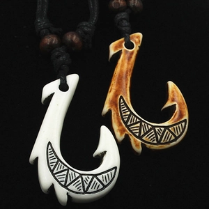 Close-up of Maori Hei Matau fish hook pendants in ivory and brown with tribal engravings