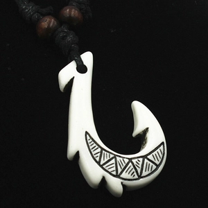 Detailed view of Maori style resin fish hook pendant with tribal carvings on black cord
