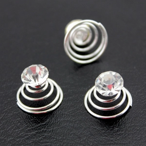 Three spiral hair pins with clear rhinestone studs on a black textured background