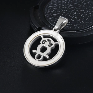 Polished stainless steel owl pendant with white shell inlay on a dark background