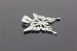 Macro detail of a silver stainless steel butterfly pendant with hollow flame wing patterns
