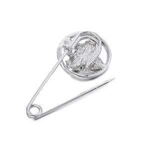 Élégante broche épingle de nourrice argentée avec motif floral évidé sur fond blanc