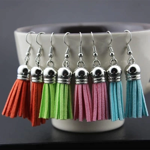 Set of eight Bohemian velvet tassel earrings with metal hooks displayed on a ceramic cup