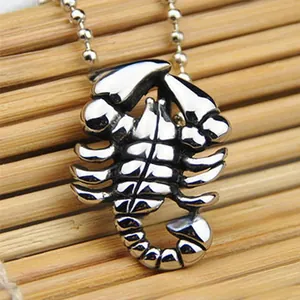 Détail macro d'un collier pendentif scorpion argenté sur un tapis en bambou