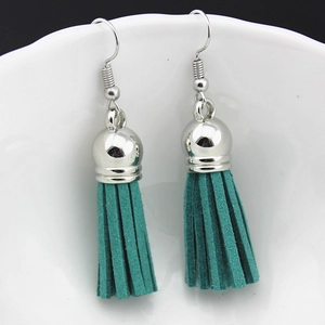 Close-up of Bohemian teal blue faux suede tassel earrings on a white porcelain edge