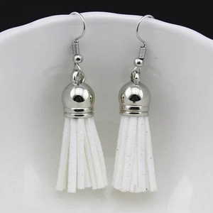 Detail of white suede fringe earrings with silver metal hooks on a porcelain edge