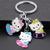 Detail of metal keychain with three colorful enamel cartoon cat figures on skateboards