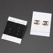 Close-up of interlocking C-shaped stud earrings in gold and black on fashion jewelry card