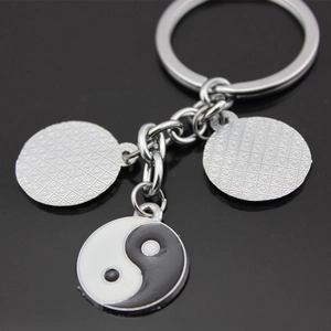 Yin Yang stainless steel keychain with three circular pendants on reflective surface