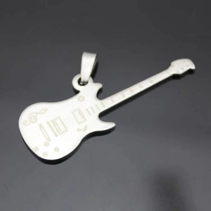 Vue détaillée du pendentif guitare argenté montrant les notes et la texture métallique