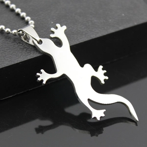 Vue macro d'un pendentif lézard en acier inoxydable argenté avec reflet sur fond noir