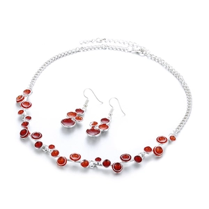 Détail d'une parure en alliage avec pendentifs ronds en émail rouge et paillettes
