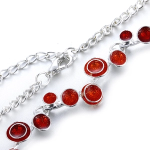 Détail de la chaîne argentée avec pendentifs en résine rouge pailletée et fermoir mousqueton