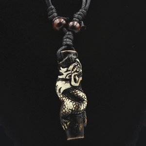 Close-up of vintage resin dragon totem pendant with intricate carving on a black cord