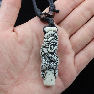 Detail view of a resin dragon totem pendant held in hand with black woven cord