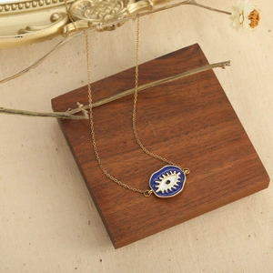Golden necklace with blue evil eye heart pendant on vintage background