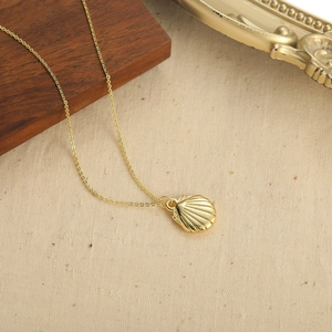 Vintage golden necklace featuring a glossy scallop shell pendant on a thin cross-link chain