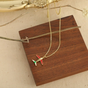 Collana con ciondolo aereo dorato con smalto rosso e verde su una catena a croce fine