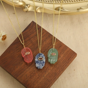 Three gold Hamsa Hand necklaces with pink blue and green stone pendants and red gems