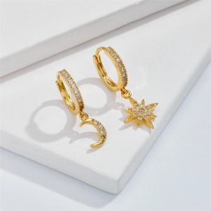 Detailed macro view of asymmetric gold hoop earrings with star and moon zircon charms