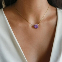 Close-up of minimalist gold chain necklace with raw purple amethyst stone pendant worn on neck