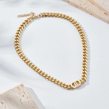 Detailed view of golden Cuban link necklace with a central CD logo and lobster clasp