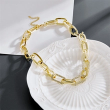 Detail of gold chunky link necklace with sparkling crystals in a white ceramic dish