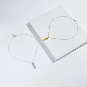 Detail view of 2021 pendant necklaces in silver and gold on white geometric stands