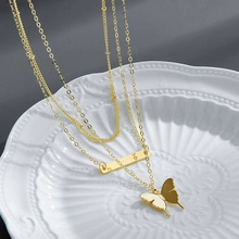 Detailed view of triple-layered gold necklace with butterfly and geometric bar pendants