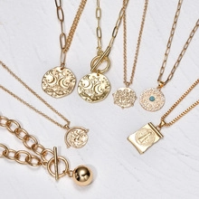 Close-up of gold plated layered necklaces with celestial coin charms and turquoise details