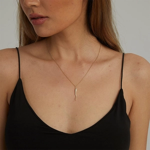 Elegant gold Italian horn pendant necklace on a delicate chain worn by a female model