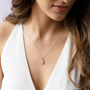 Detail van roze steen hanger met 14K vergulde ketting om de hals van model
