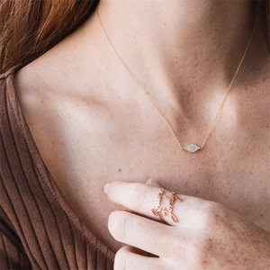 Détail du collier œil d'opale et de la bague personnalisée en or rose portée par un mannequin