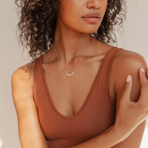 Close-up of minimalist freshwater pearl necklace on model with five white pearls in gold