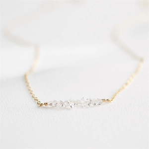 Macro detail of 14K gold plated wire-wrapped natural white crystal pendant necklace
