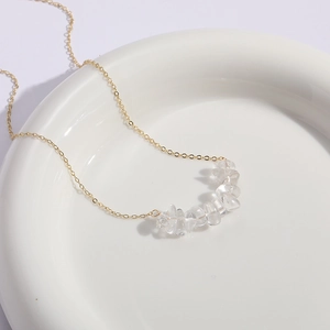 Collar minimalista de oro con colgante de cristal natural sobre bandeja de cerámica