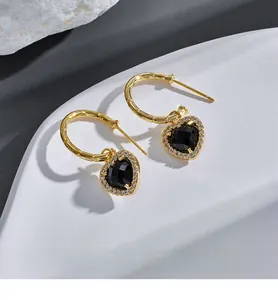Macro shot of vintage gold heart earrings with black stone and pave zircon details