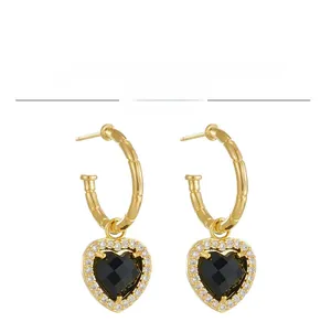Close-up of golden bamboo heart earrings featuring black stones and white zircons