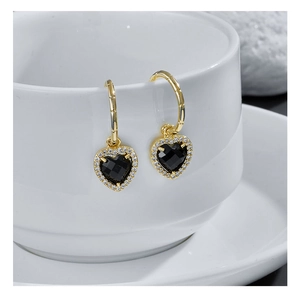 Golden bamboo texture hoop earrings with black heart zircon pendant on ceramic cup