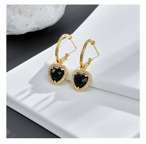 Detailed macro shot of heart earrings with black stone and gold bamboo hoop design